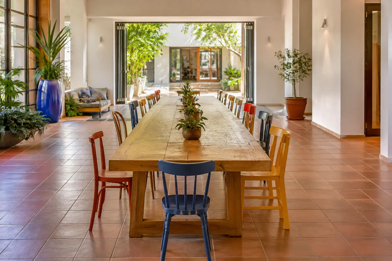 Long community table surrounded by varied colorful chairs in a bright civic space